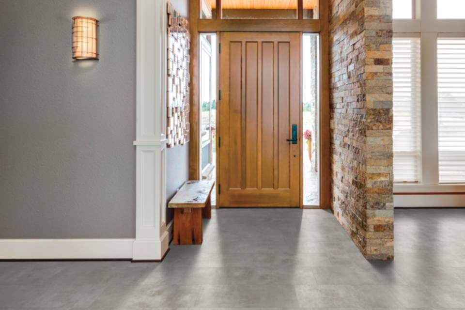 stone luxury vinyl tile flooring in entryway with stone accent wall and wood door.